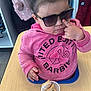 accessories, bag, child, clothing, eating, face, female, food, furniture, girl, glasses, handbag, head, indoors, person, photography, portrait, sunglasses, sweets, t_shirt