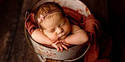 Paisley joined the competition — help win amazing prizes! newborn, baby, sleeping, bucket, blanket, headband, pink, flower, arms, closeup, portrait, infant, peaceful, rustic, wooden_floor, cozy, cute, soft_light, hands, skin