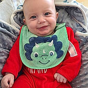 Lewis participe au concours pour gagner de l'argent avec cette photo : baby, infant, child, smiling, bib, dinosaur_bib, red_onesie, blanket, bouncer, socks, blue_eyes, face, portrait, hand, cheeks, seat, cute, indoors, backpack, happy