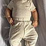 baby, bedroom, changing_pad, child, clothing, comfort, curious_expression, cute, face, footed_pajamas, hands, head, indoors, infant, lying_down, nike_logo, onesie, pants, skin, soft_lighting