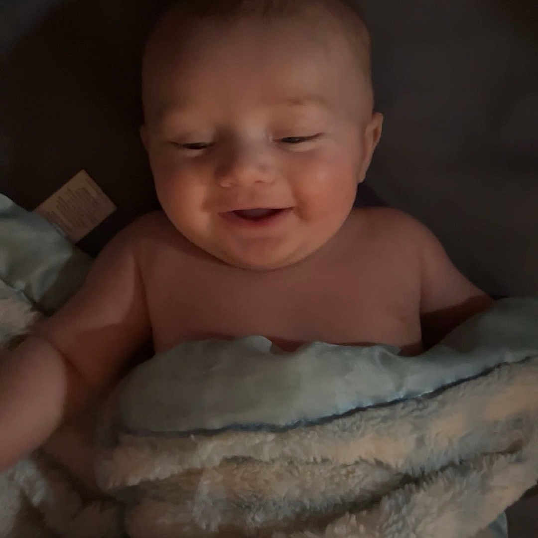 Remington is registered to the contest to win money with this photo: baby, bed, bedroom, blanket, face, furniture, happy, head, indoors, newborn, person, photography, portrait, quilt, room, sleeping, smile, towel