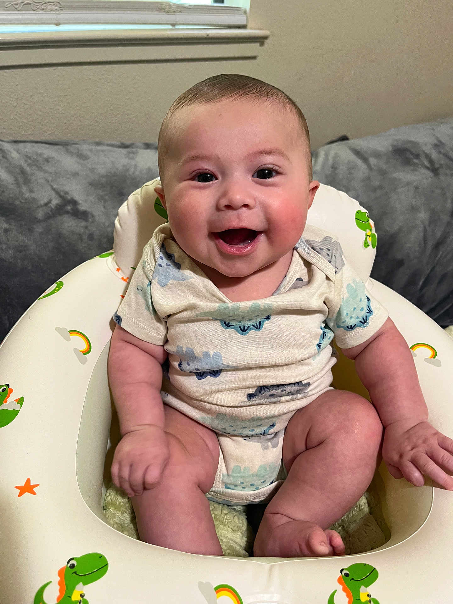 Mason joined the competition — help win amazing prizes! baby, smiling, infant, child, dinosaur, baby_seat, cute, happy, indoor, onesie, chubby, sitting, face, skin, human, portrait, couch, window, room, toy