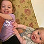Paige is registered to the contest to win money with this photo: toddler, child, smile, happy, playful, couch, floral_pattern, indoor, clothing, person, face, baby, joy, fun, blur, hands, purple_shirt, striped_shirt, living_room, young