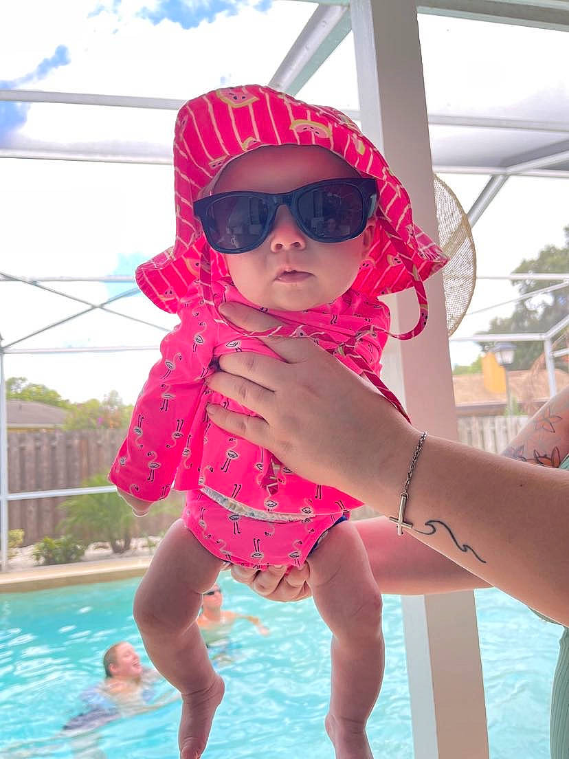 Haisley is registered to the contest to win money with this photo: arm, blue, blurred, child, fun, glasses, goggles, hand, happy, headwear, human_body, leg, leisure, person, pink, plant, recreation, red, sunglasses, swimming_pool