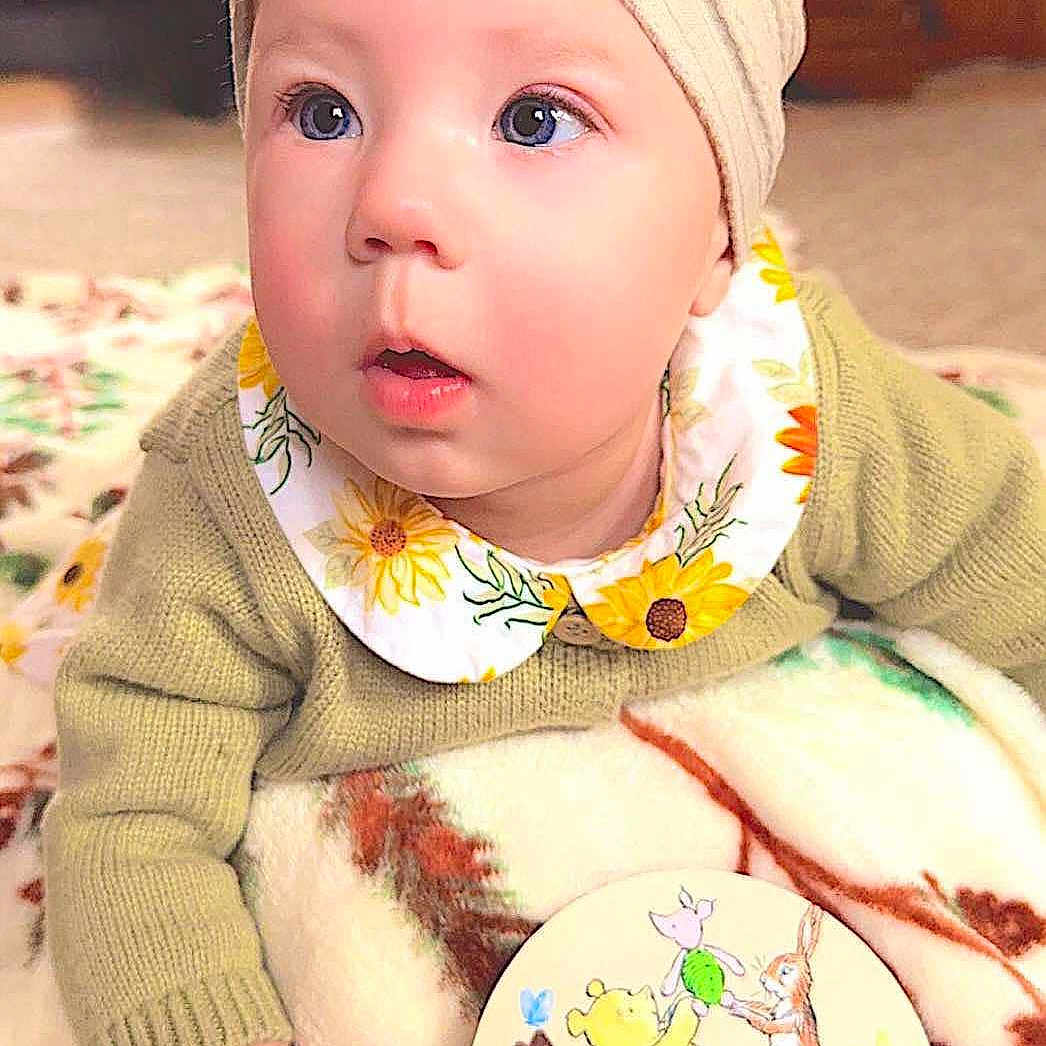 Marissa is registered to the contest to win money with this photo: accessories, baby, bonnet, cap, clothing, costume, face, furniture, hat, head, headband, knitwear, person, photography, portrait, quilt, sitting, sweater, toy, turban