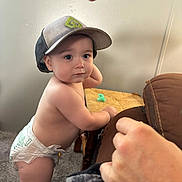 Jameson joined the competition — help win amazing prizes! baby, baseballcap, bodypart, cap, clothing, couch, diaper, eating, face, finger, food, furniture, hand, hat, head, person, photography, portrait, shorts, sitting