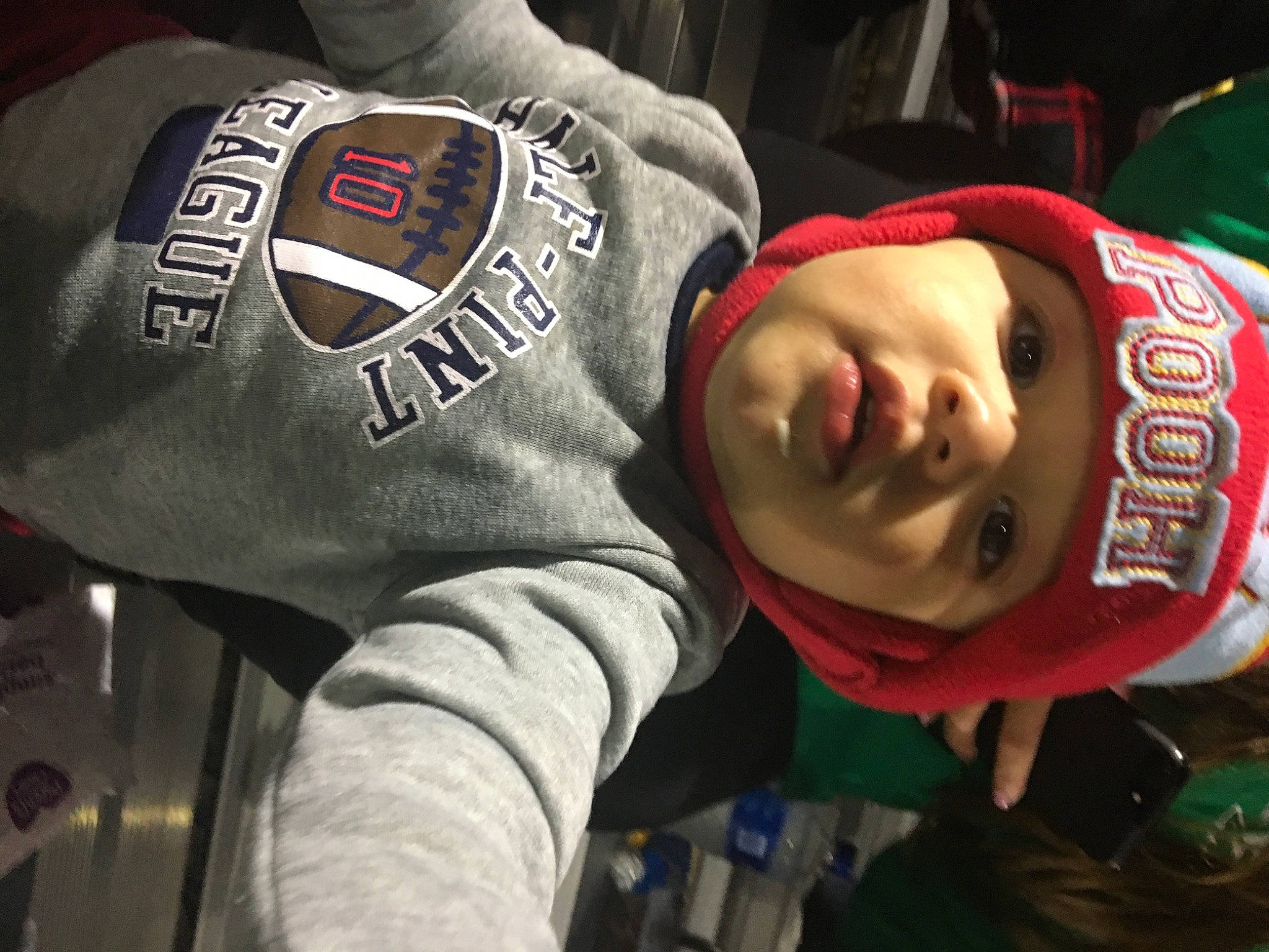 Kylan is registered to the contest to win money with this photo: cap, carmine, championship, competition_event, elbow, fan, fashion_accessory, headwear, logo, person, personal_protective_equipment, recreation, sleeve, smile, sports_gear, sportswear, team, toddler, uniform