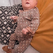 Jade participe au concours pour gagner de l'argent avec cette photo : baby, infant, leopard_print, headband, slippers, pillow, blanket, cozy, sparkles, cute, indoors, clothing, child, person, soft_texture, smiling, resting, patterned_clothing, comfortable, young_child