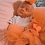 baby, sleeping, flower_headband, orange_tulle, white_onesie, pink_blanket, soft_fabric, peaceful, infant, closeup, portrait, indoors, resting, cute, newborn, baby_clothing, head_accessory, cozy, tulle, soft_lighting