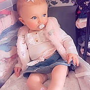 Jade participe au concours pour gagner de l'argent avec cette photo : baby, child, pacifier, pink_bow, blue_eyes, denim_skirt, pink_shoes, blanket, clothing, soft_toys, indoors, wallpaper, floral_pattern, cute, seated, infant, vest, long_sleeve_shirt, floor, comfort