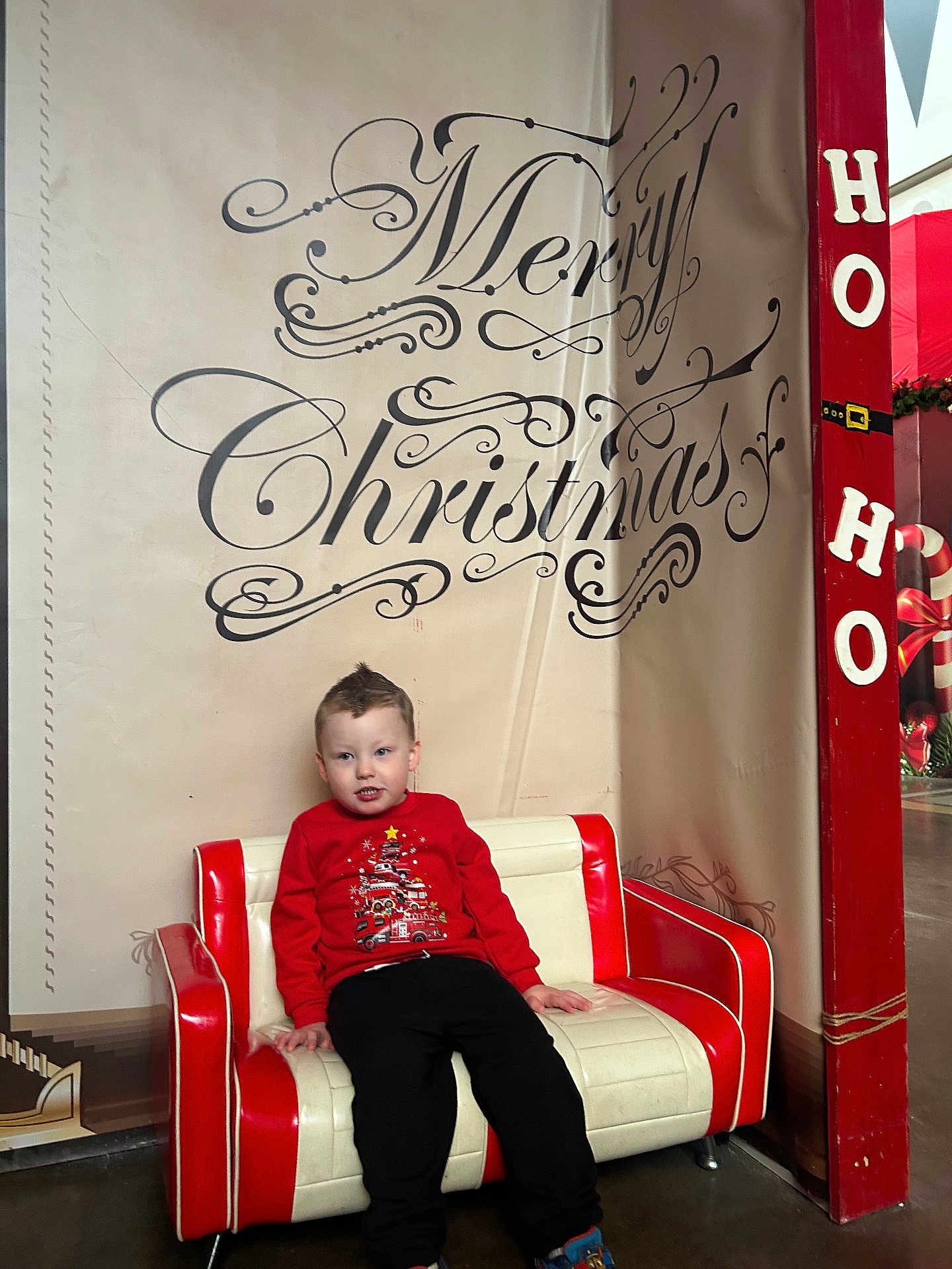 Ace joined the competition — help win amazing prizes! child, christmas, holiday, red_sweater, couch, indoor, decor, festive, smiling, person, wall_text, red_and_white, pants, shoes, floor, pillar, ho_ho, background, pose, cute