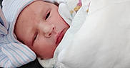Rayne is registered to the contest to win money with this photo: newborn, baby, infant, blanket, hat, sleepy, wrapped, cozy, closeup, face, soft, cute, child, person, indoors, warm, headwear, newborn_clothing, resting, portrait