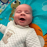 Lillie-Mai is registered to the contest to win money with this photo: baby, smiling, infant, play_mat, quilted_clothing, bear_embroidery, happy, face, child, cute, indoors, colorful, cartoon, turtle, orange, blue, white, person, portrait, joyful