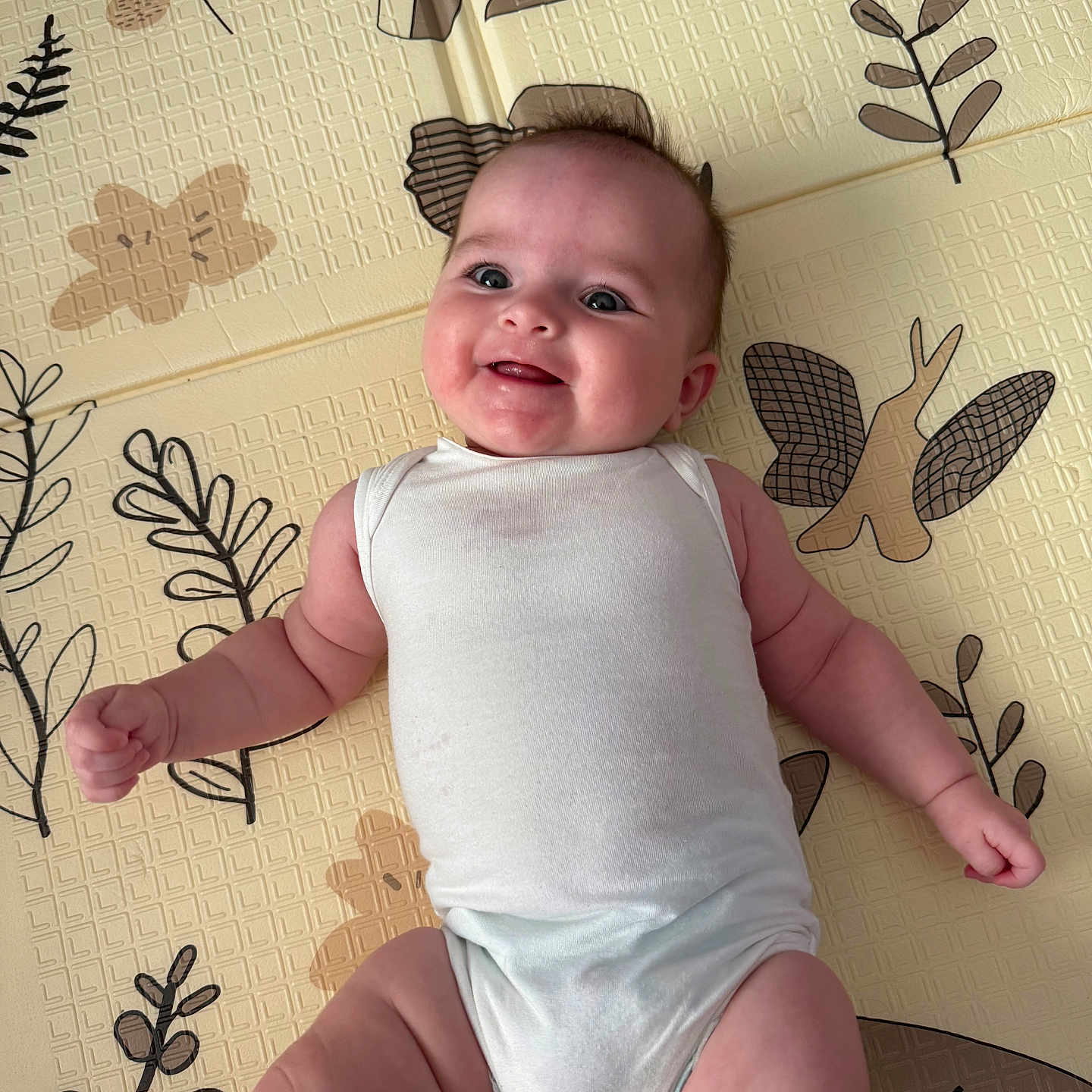 Hannah participe au concours pour gagner de l'argent avec cette photo : arm, baby, babywear, child, cute, fabric, face, happy, head, indoor, infant, leg, lying_down, onesie, pattern, person, play_mat, skin, smiling, young