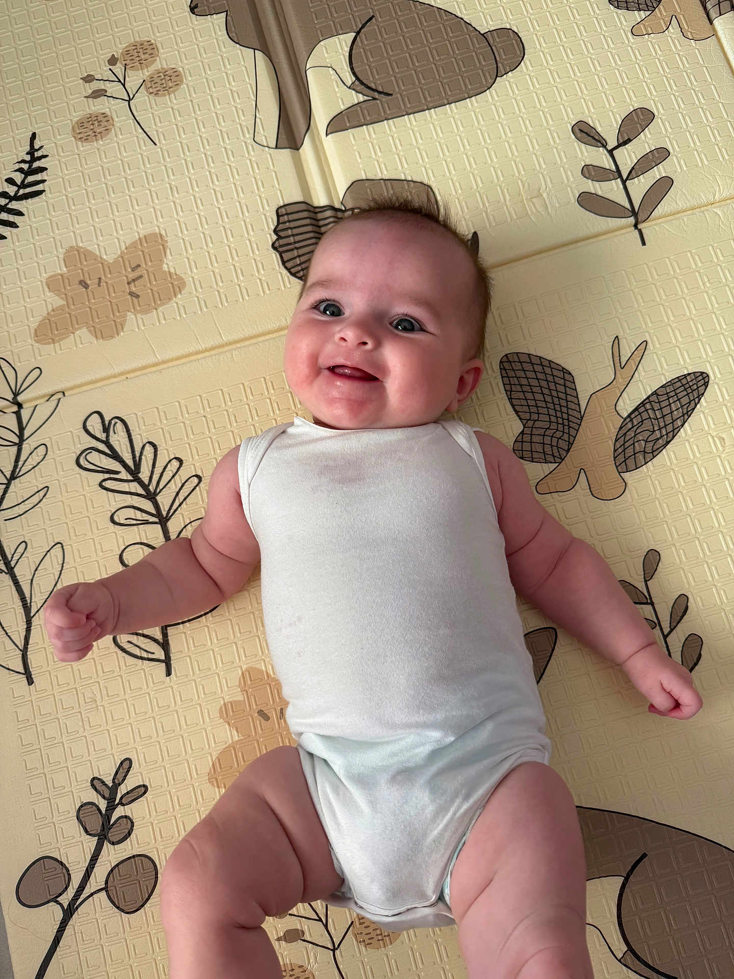 Hannah participe au concours pour gagner de l'argent avec cette photo : baby, smiling, infant, onesie, play_mat, child, cute, happy, lying_down, skin, arm, leg, head, face, indoor, pattern, fabric, person, young, babywear