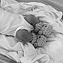 baby, blanket, knitted_booties, infant, sleeping, cozy, monochrome, soft_texture, clothing, footwear, bed, indoors, newborn, cute, resting, wrapped, fabric, warm, small, toddler