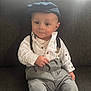baby, cap, casual, child, clothing, couch, cute, face, fashion, hat, indoor, pants, person, portrait, seated, shirt, sitting, smiling, suspenders, young