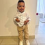Kendy participe au concours pour gagner de l'argent avec cette photo : child, toddler, smile, boy, white_shirt, bow_tie, beige_pants, white_sneakers, standing, indoors, tile_floor, wall, happy, cute, fashion, portrait, person, shadow, curly_hair, bright