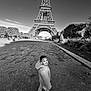 Kendy participe au concours pour gagner de l'argent avec cette photo : black_and_white, boy, child, daytime, eiffel_tower, footpath, happy, jacket, landmark, monument, outdoor, park, scenic, shoes, sky, smile, tourist, travel, trees, urban
