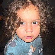 Kai is registered to the contest to win money with this photo: child, toddler, curly_hair, blue_sweater, cartoon_characters, face, eyes, lips, food, close_up, indoor, portrait, person, cute, young, looking, expression, hair, sweater, childhood