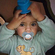 Nolhan a rejoint le concours — aidez-le/la à gagner de superbes lots ! baby_clothing, cartoon_lion, child, close_up, cup, curious, eyes, face, hands, hat, headwear, holding_object, indoor, pacifier, playful, portrait, simba, sweatshirt, toddler, young_child