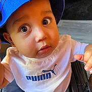 Isaac Jr is registered to the contest to win money with this photo: toddler, child, baby, blue_hat, bucket_hat, white_tshirt, puma_logo, drool, wide_eyes, curious, close_up, indoor, person, cute, young_child, expression, face, hand, sitting, portrait