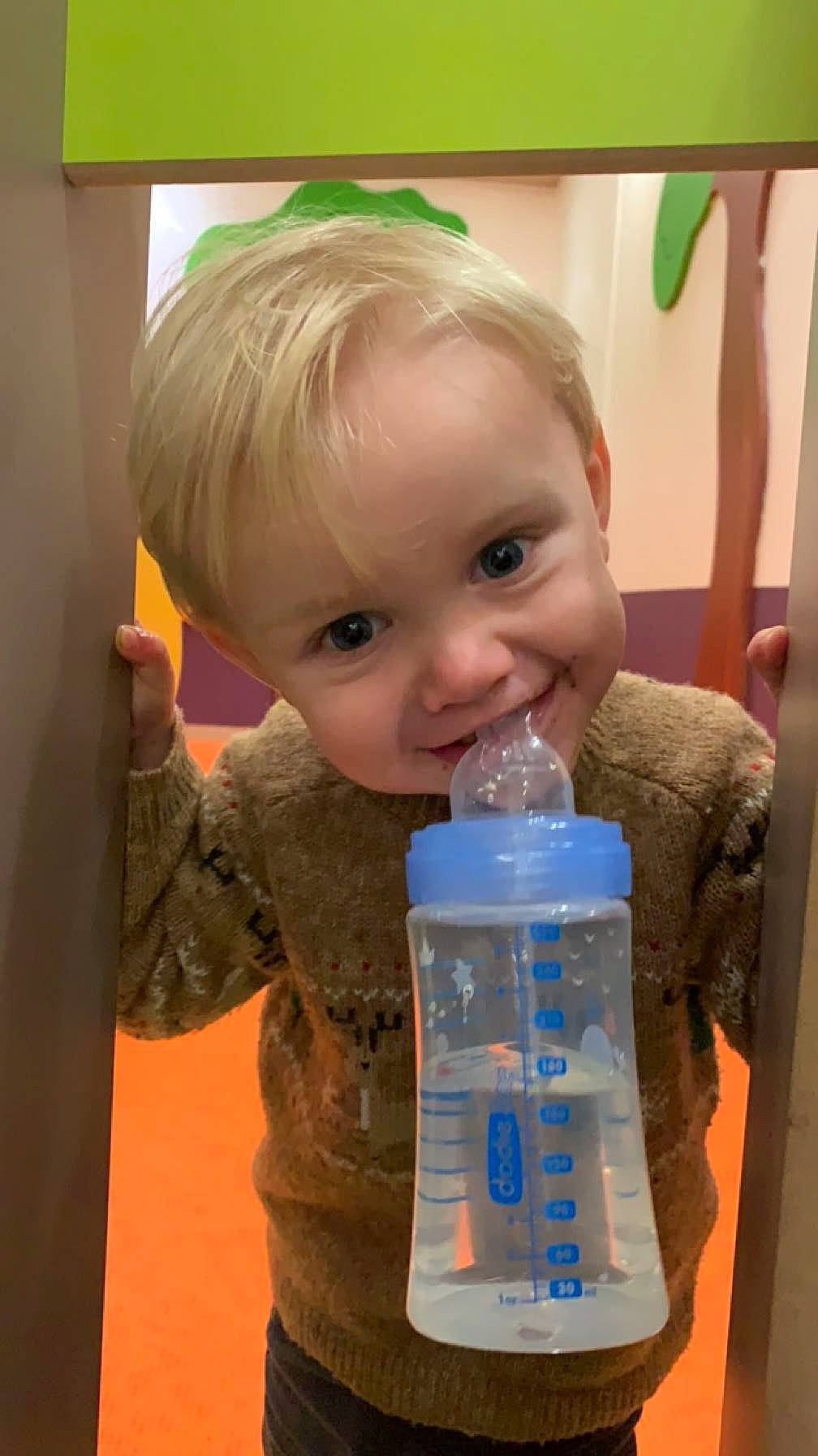 Lyam a rejoint le concours — aidez-le/la à gagner de superbes lots ! baby, baby_toddler_clothing, child, drink, drinking, drinkware, electric_blue, finger, fun, green, hand, happy, person, plastic, plastic_bottle, room, smile, solvent, standing, thumb