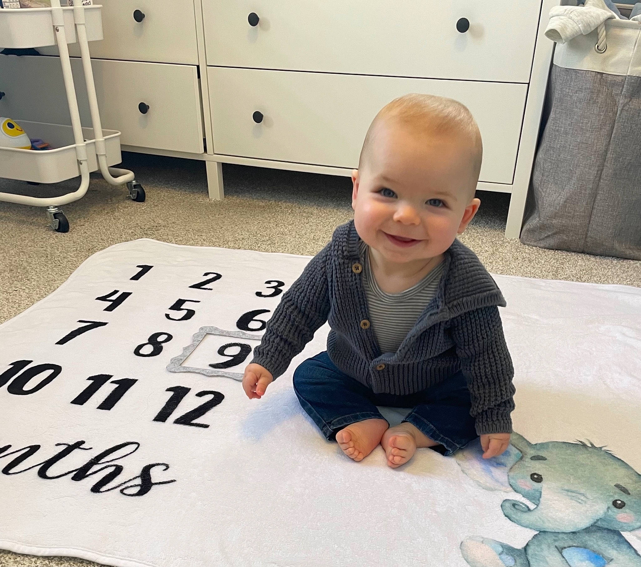 Calum is registered to the contest to win money with this photo: baby, baby_toddler_clothing, black, cabinetry, eye, floor, flooring, happy, head, joint, joy, people, person, photograph, product, skin, smile, snapshot, t_shirt, toddler