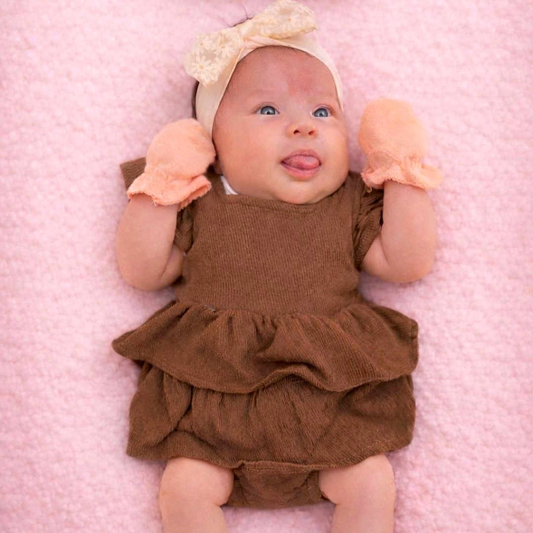 Analucia joined the competition — help win amazing prizes! baby, blanket, bow, brown_dress, cheeks, child, clothing, cute, dress, eyes_open, fabric, face, headband, infant, lying_down, mittens, pink_blanket, portrait, soft_texture, tongue_out