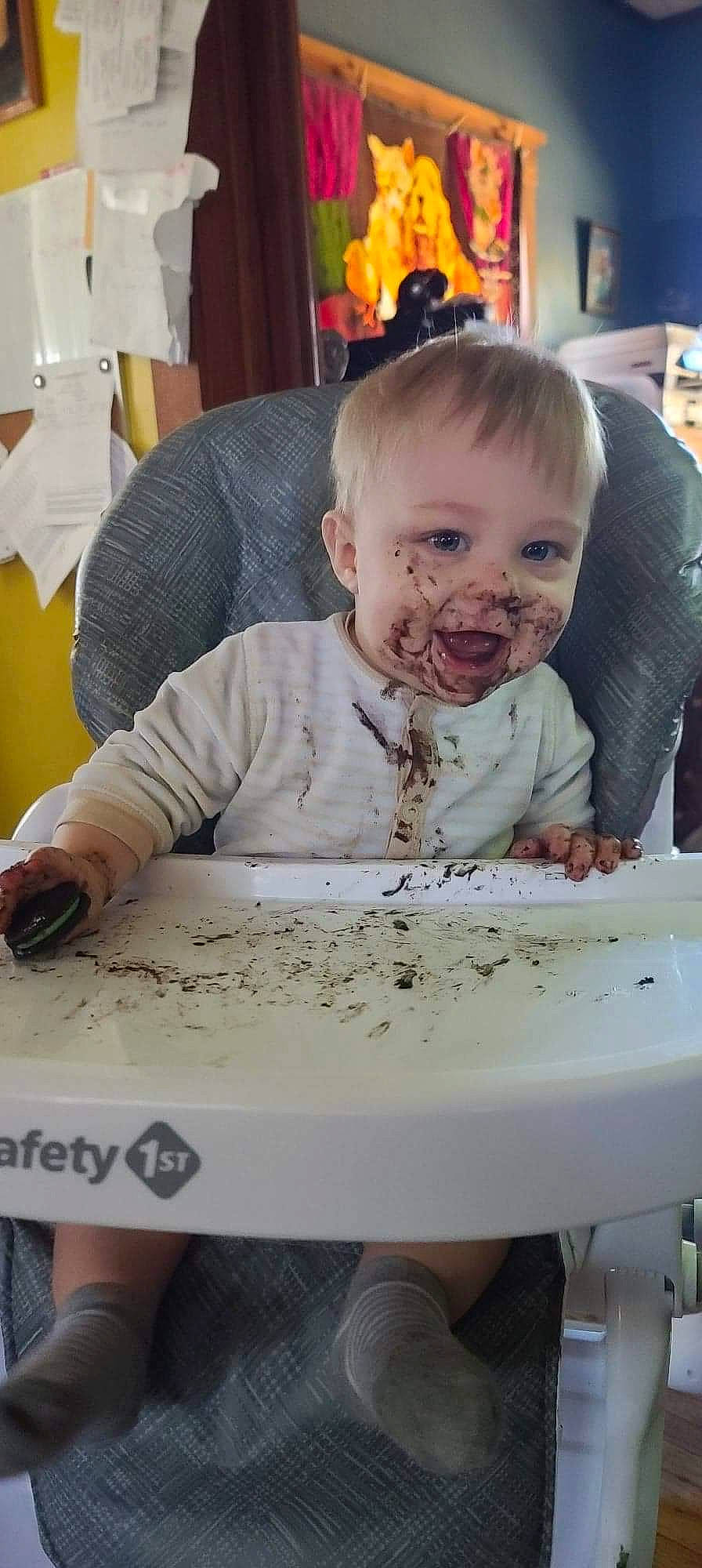 Francis is registered to the contest to win money with this photo: baby, chair, cheek, child, comfort_food, eating, flooring, fun, hairstyle, happy, person, play, room, sitting, smile, snapshot, table, toddler, wood