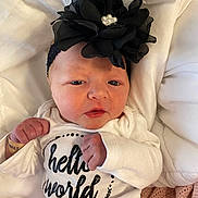 Winsley joined the competition — help win amazing prizes! newborn, baby, infant, headband, black_flower, onesie, hello_world, white_clothing, blanket, soft_texture, fist, portrait, cute, small_hands, lying_down, indoors, closeup, face, skin, expression