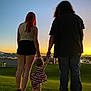 Xalia is registered to the contest to win money with this photo: sunset, child, adult, holding_hands, grass, hill, sky, mountains, suburban, building, person, silhouette, evening, outdoor, nature, family, toddler, casual_clothing, scenic, twilight