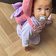 Keylia a rejoint le concours — aidez-le/la à gagner de superbes lots ! baby, pacifier, crawling, plush_backpack, pink, butterfly, wooden_floor, indoors, child, cute, infant, clothing, person, young_child, face, head, eyes, hand, toy, flooring
