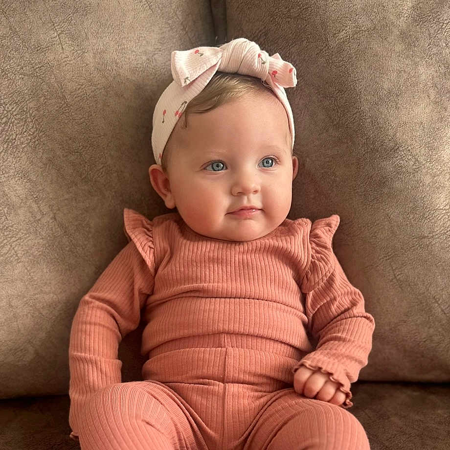 Poppy-Mae is registered to the contest to win money with this photo: accessories, baby, clothing, couch, cushion, face, furniture, happy, hat, head, headband, homedecor, newborn, pants, person, photography, portrait, sitting, sleeve, smile