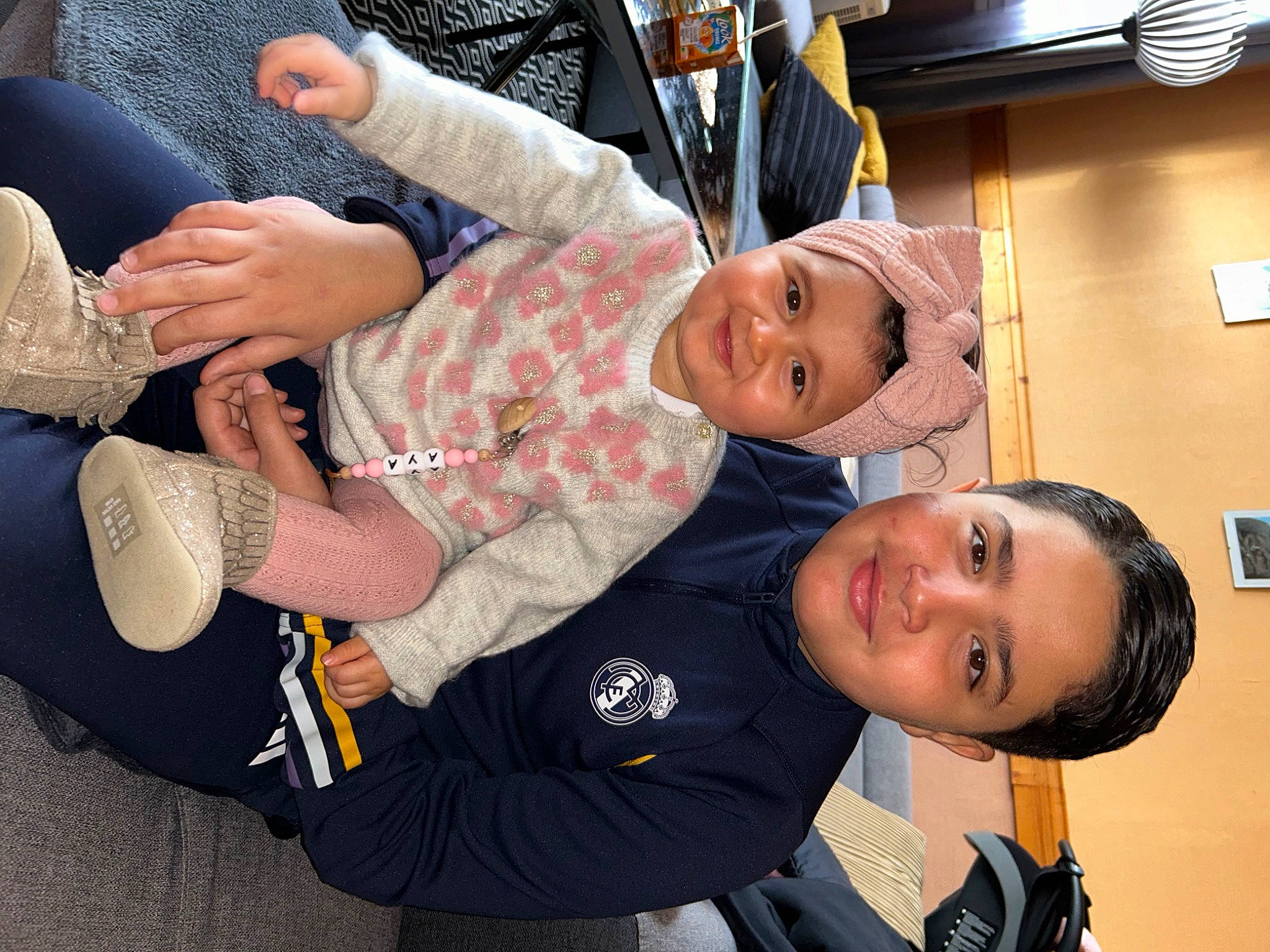 Aya participe au concours pour gagner de l'argent avec cette photo : baby_toddler_clothing, child, comfort, elbow, foot, fun, gesture, happy, headwear, human_leg, joint, joy, knee, lap, mouth, person, sitting, sleeve, smile, thigh