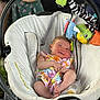 baby, infant, baby_rocker, toy, bottle, colorful_clothing, outdoor, baby_toys, smile, face, person, seat, fabric, playful, comfort, relaxation, child, cute, winking, happy