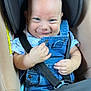 baby, child, car_seat, denim_overalls, smiling, blue_eyes, infant, clothing, safety_harness, cute, person, seatbelt, happy, young_child, indoor, portrait, casual, head, hands, expression