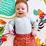baby, infant, smiling, play_mat, toy, colorful, cute, portrait, happy, toddler_like, shorts, onesie, lying_down, indoors, cheerful, child, playtime, soft_toy, developmental_toy, nursery