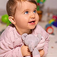 Loucia participe au concours pour gagner de l'argent avec cette photo : baby, child, blue_eyes, smiling, plush_toy, elephant_toy, pink_clothing, cute, happy, indoor, portrait, infant, soft_toy, toddler, barefoot, closeup, face, skin, hair, expression