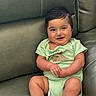 Mahir is registered to the contest to win money with this photo: baby, infant, smiling, cute, onesie, green_clothing, volcano_print, sitting, couch, leather, indoors, child, happy, portrait, chubby_cheeks, hand_position, short_hair, skin, face, young