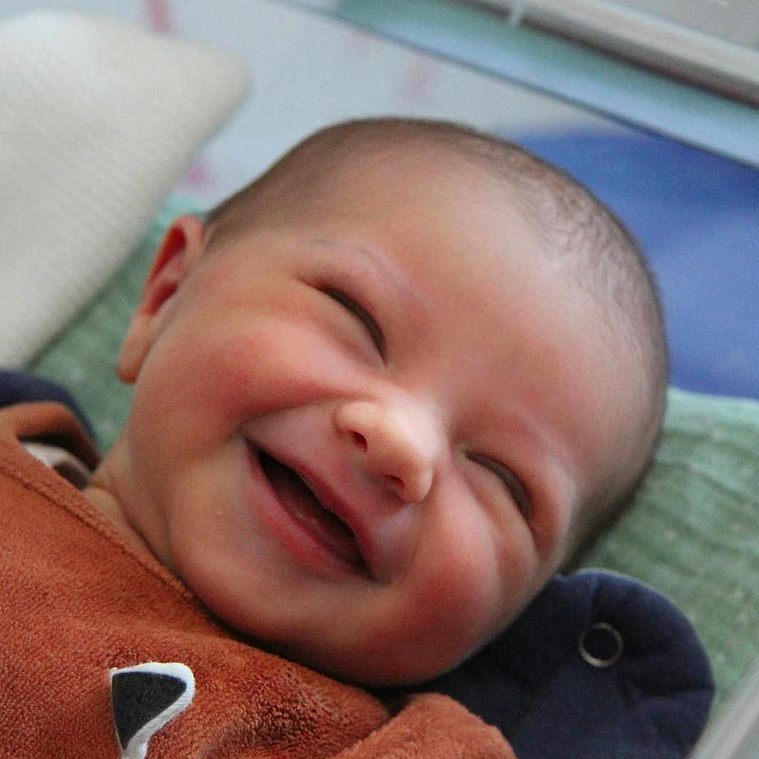 Ambre participe au concours pour gagner de l'argent avec cette photo : baby, blanket, brown_clothing, child, closeup, comfort, cozy, cute, expression, face, happy, head, indoors, infant, pillow, portrait, resting, skin, smiling, young