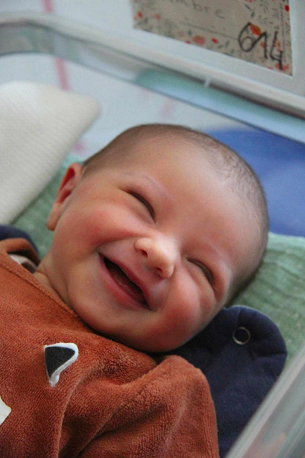 Ambre participe au concours pour gagner de l'argent avec cette photo : baby, smiling, infant, face, cozy, brown_clothing, blanket, pillow, happy, cute, child, indoors, portrait, closeup, head, skin, expression, resting, comfort, young