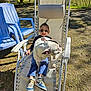 blue_pants, bulldog, casual, chair, child, dog, fence, grass, outdoor, pet, playful, recliner, relaxing, shadow, shoes, smile, sunglasses, sunny, tree, white_dog