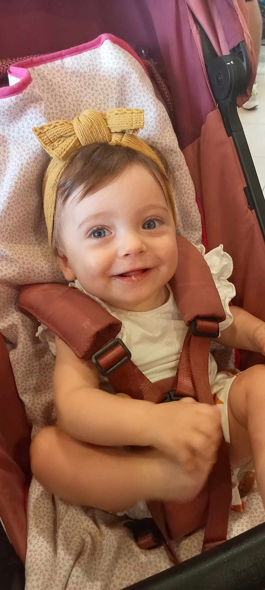 Lola a rejoint le concours — aidez-le/la à gagner de superbes lots ! baby, child, smile, headband, stroller, seatbelt, blue_eyes, clothing, happy, infant, cute, young_child, person, toddler, indoors, fabric, seat, straps, cheerful, face