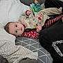 baby, infant, couch, blanket, pillow, clothing, face, person, indoor, soft, cute, child, striped, pattern, fabric, relaxed, home, comfort, laying, looking