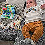 baby, child, toy, blanket, pillow, sofa, clothing, socks, indoor, home, soft_toy, giraffe_toy, pattern, cushion, floor, person, resting, casual, infant, cozy