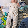 baby, infant, onesie, giraffe_print, toy, stuffed_animal, blanket, pillow, floor, jeans, child, lying_down, patterned, cute, indoor, soft_toys, playtime, comfort, clothing, person