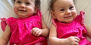 Anahi And Areli joined the competition — help win amazing prizes! baby, twins, smiling, pink_clothing, heart_patch, curly_hair, hair_bun, earrings, lying_down, white_quilt, infant, cute, happy, portrait, child, indoor, soft_lighting, two_children, matching_outfits, skin