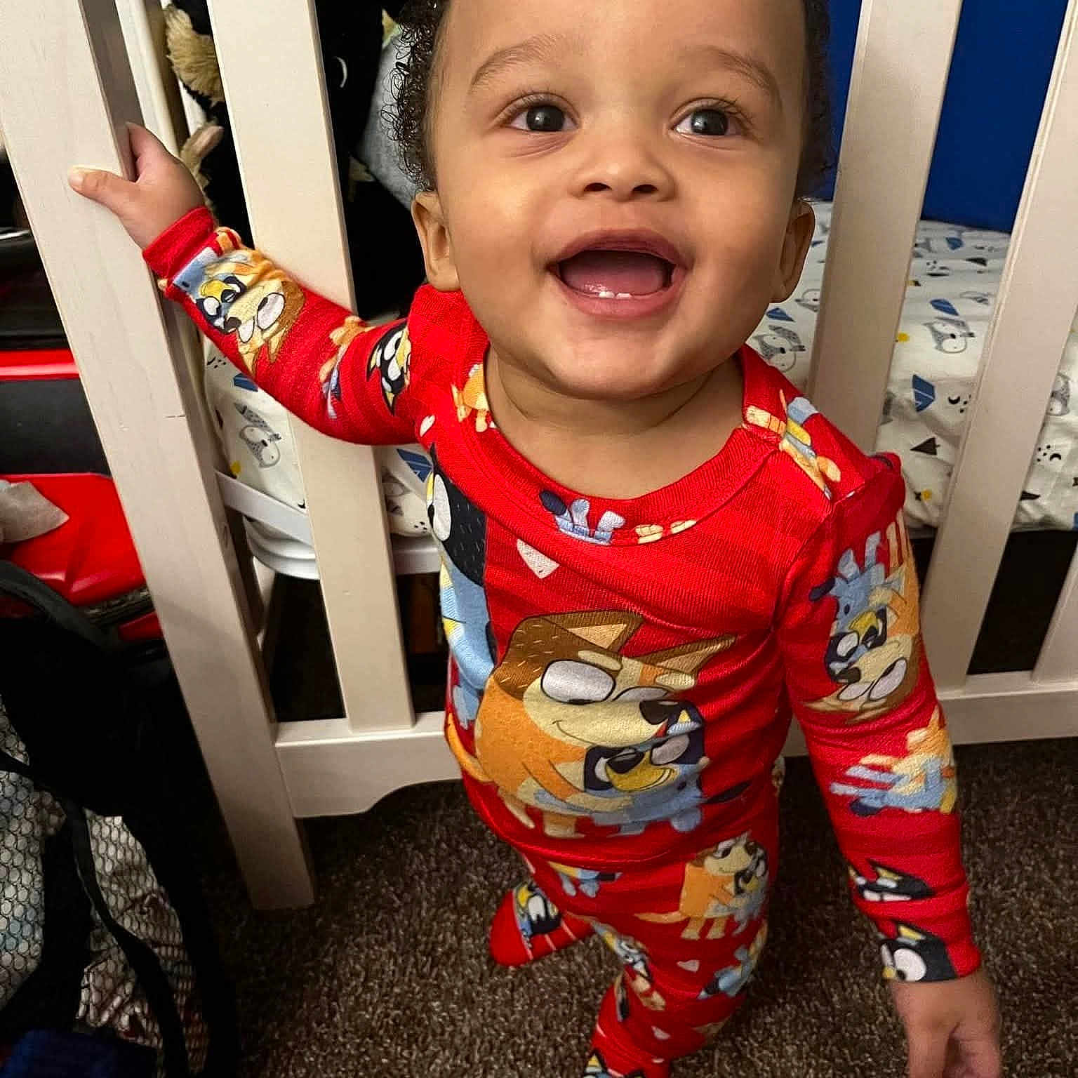 Dashine joined the competition — help win amazing prizes! toddler, child, pajamas, red_clothing, smiling, baby, crib, nursery, carpet, bed, furniture, indoor, person, happy, standing, hand, face, cute, cartoon_print, closeup