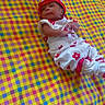 baby, infant, child, blanket, patterned_blanket, colorful, red, white, hat, clothing, lying_down, cute, small, indoors, soft, resting, portrait, young, person, happy